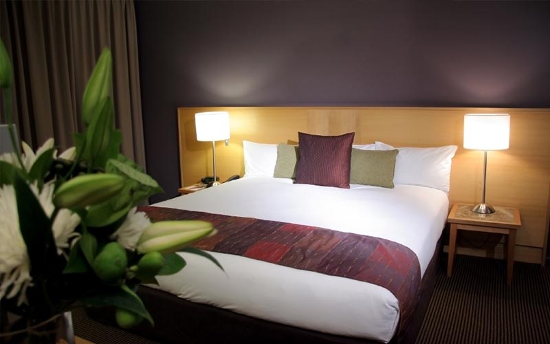 Hotelzimmer mit Bett und beleuchteten Nachttischlampen - Corporate Design Bill Immoconsult