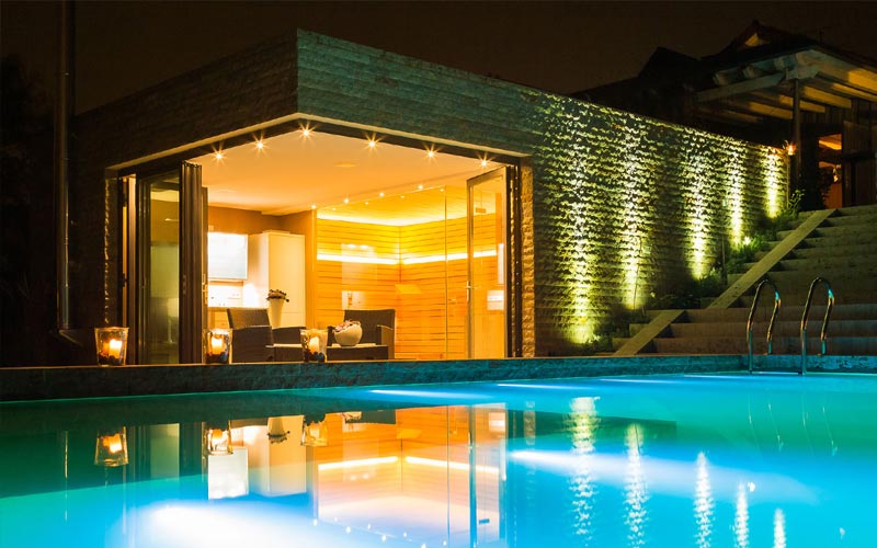 Beleuchteter Pool bei Nacht mit Blick auf den Saunabereich - Internetauftritt Team Grün (Spa)