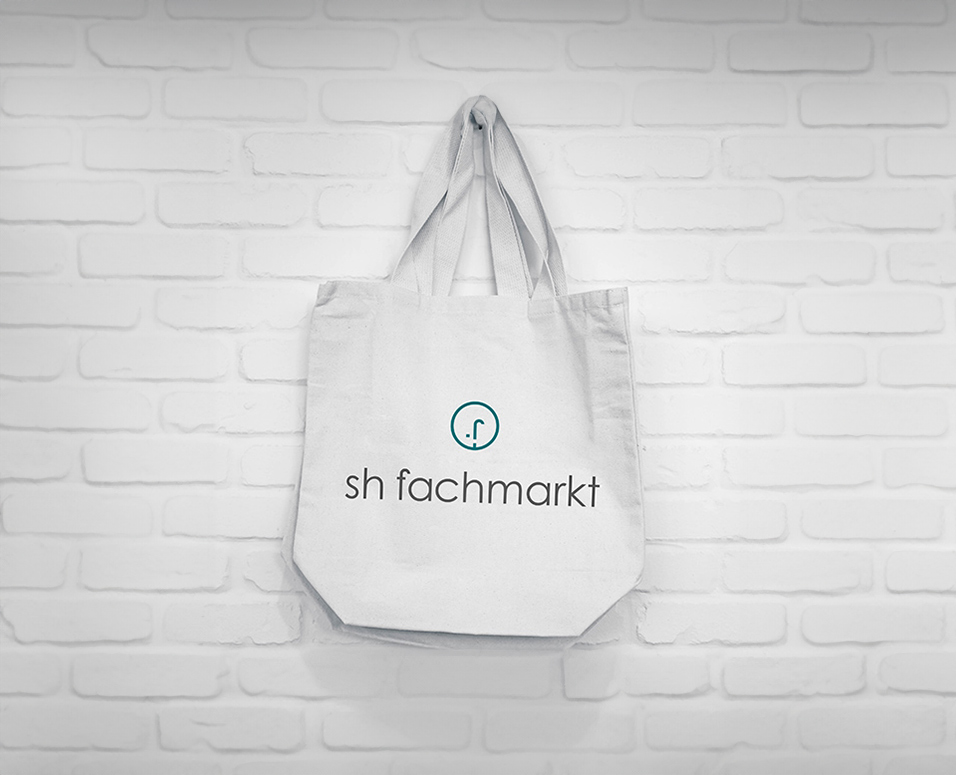 Ansicht einer weißen Tragetasche mit dem Logo des sh fachmarkt vertikal zentriert in Farbe