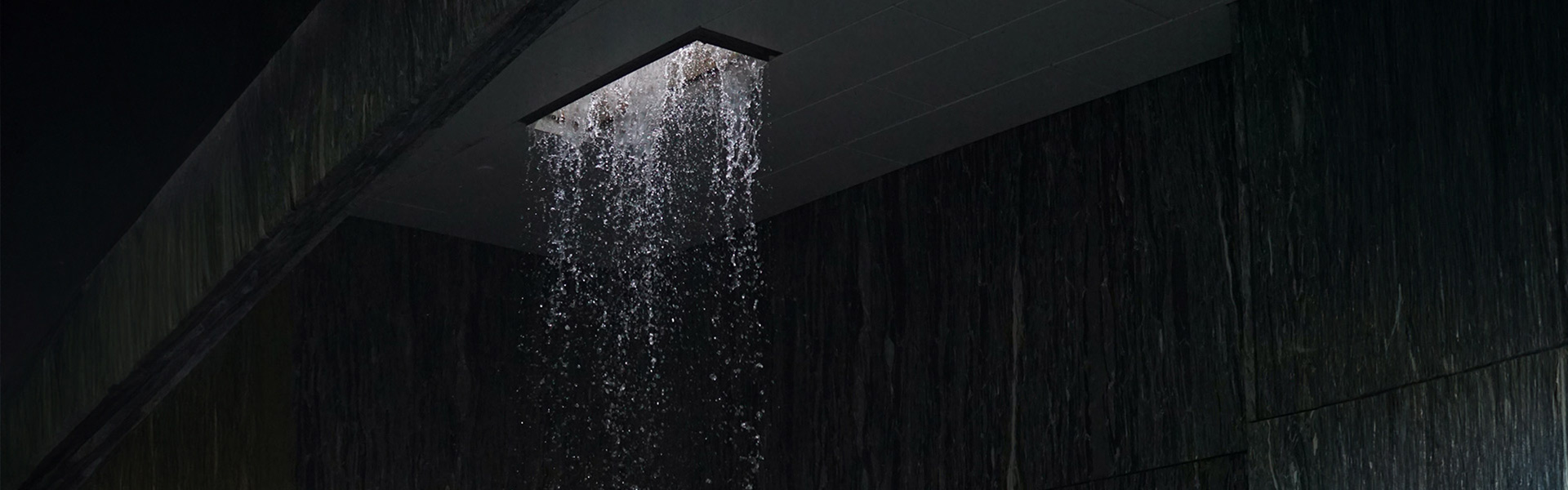 Ein beleuchteter Wasserfall-Duschkopf in einem dunklem Raum