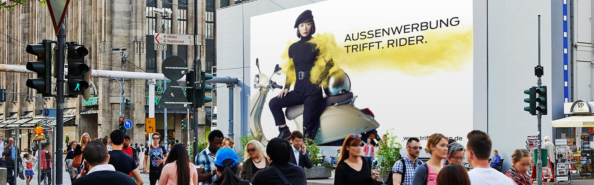 Belebte Straßenszene in europäischer Stadt zeigt eine große Plakatwerbung einer Frau in Schwarz auf einem Roller