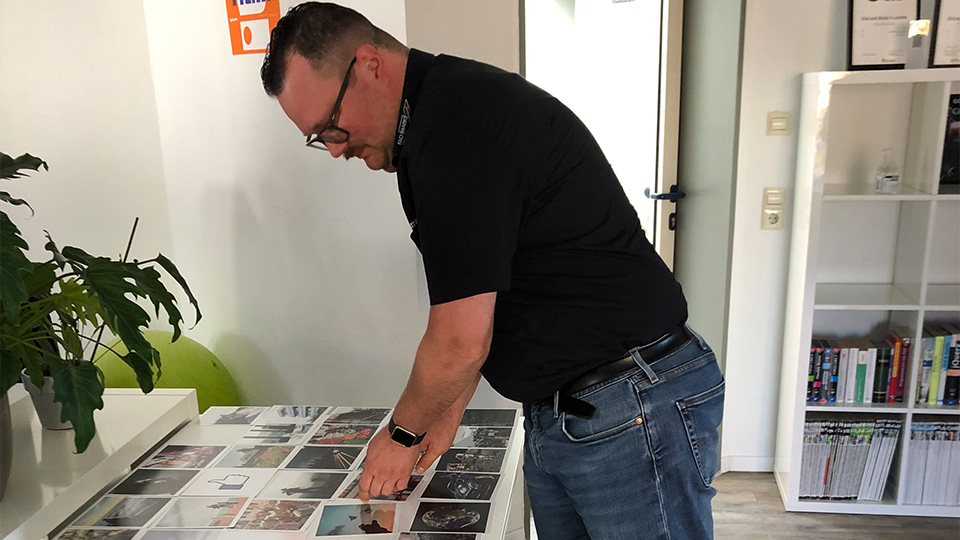 Workshopsituation in der eine Person vor einem Tisch voller Bilderkarten steht und sich eine davon aussucht