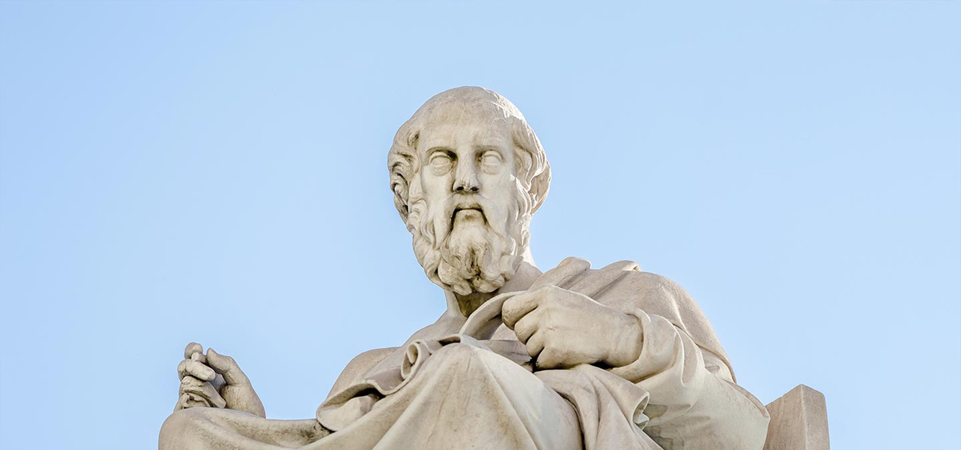 Statue einer bärtigen, männlichen Figur in klassischer Robe, die sitzend eine Schriftrolle hält