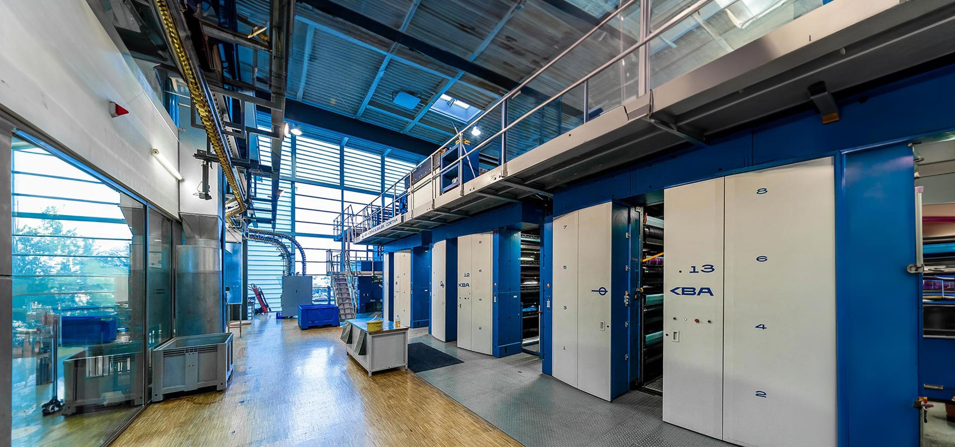 Große industrielle Druckmaschine mit blau-weißer Maschinerie, Bedienfeldern und Rohren