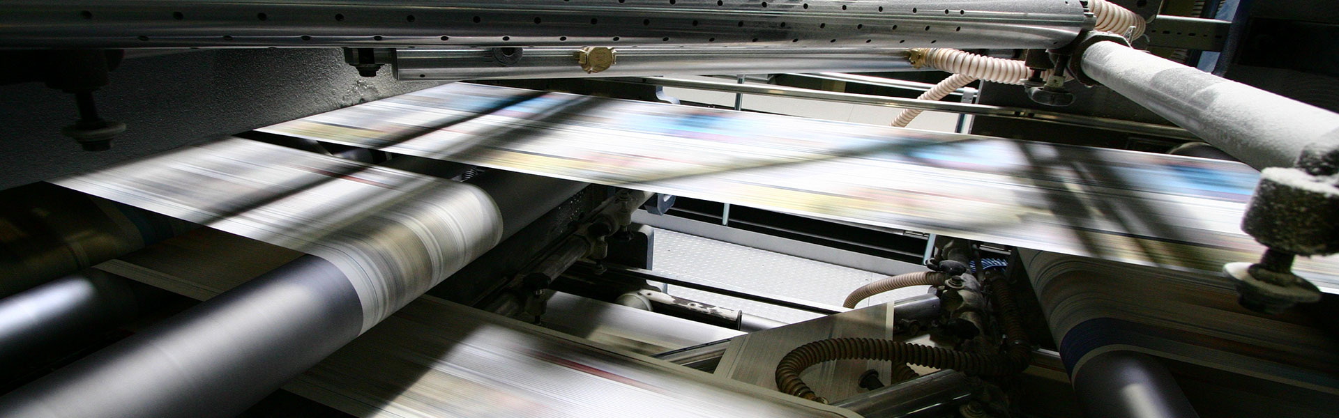 Nahaufnahme einer Druckmaschine im Betrieb, bei der Papierblätter schnell durch die Walzen laufen