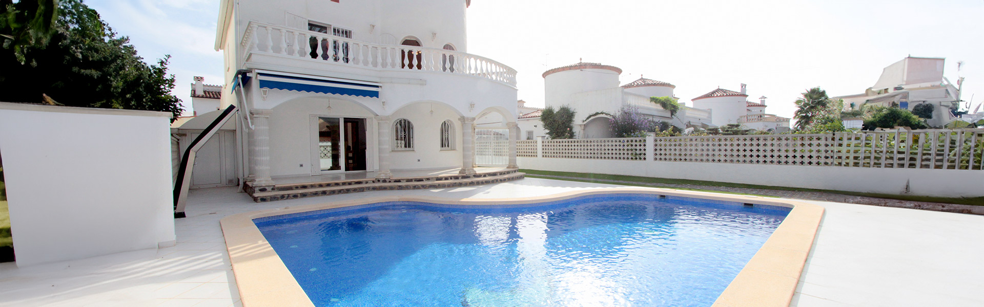 Ein Blauer Pool in einem weiten Hof vor einer weißen Immobilie in Spanien