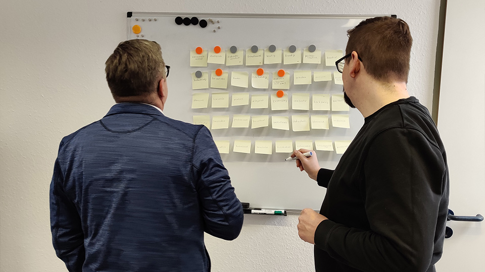 Workshopsituation mit zwei Personen von Maker Menz vor einem White Board mit Post-Its daran