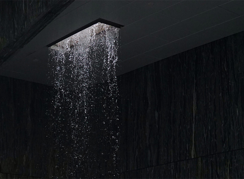 Ein beleuchteter Wasserfall-Duschkopf in einem dunklem Raum