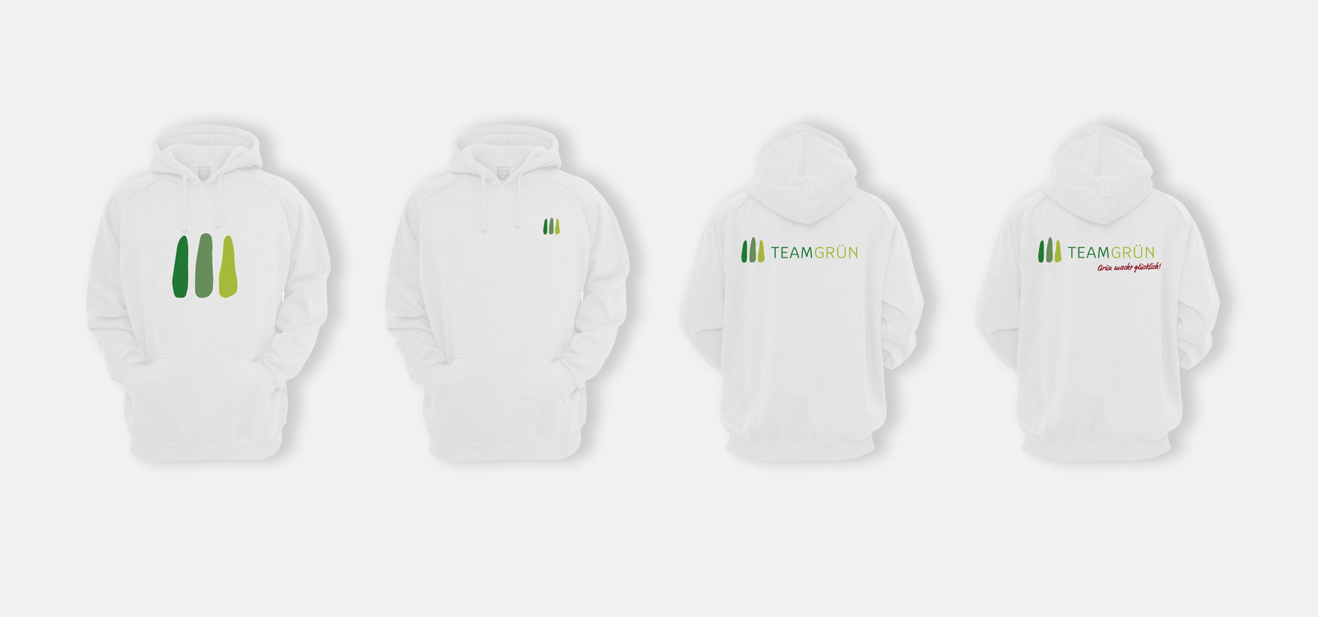 Ansicht von vier weißen Hoodies mit jeweils leicht unterschiedlichen Aufdrucken des Logos von Team Grün