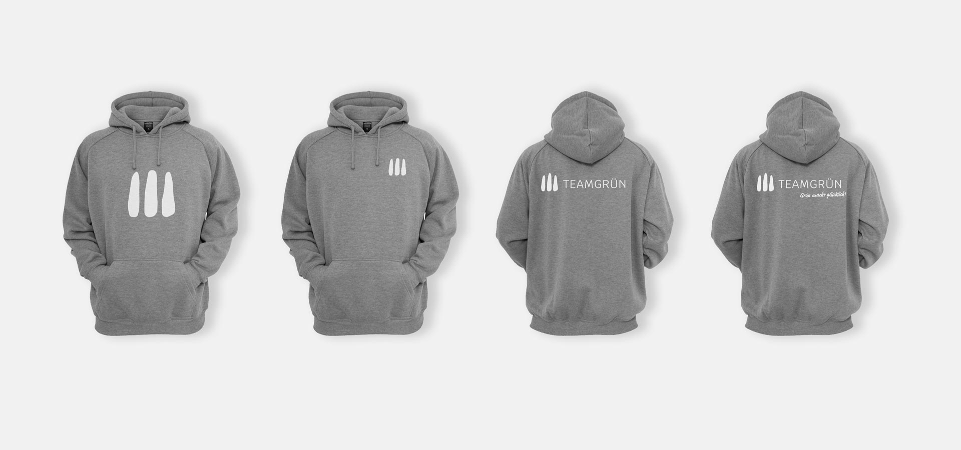 Ansicht von vier grauen Hoodies mit jeweils leicht unterschiedlichen Aufdrucken des Logos von Team Grün