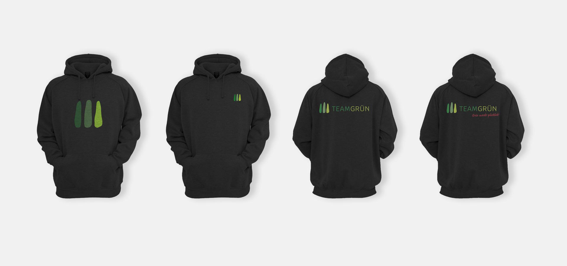 Ansicht von vier schwarzen Hoodies mit jeweils leicht unterschiedlichen Aufdrucken des Logos von Team Grün