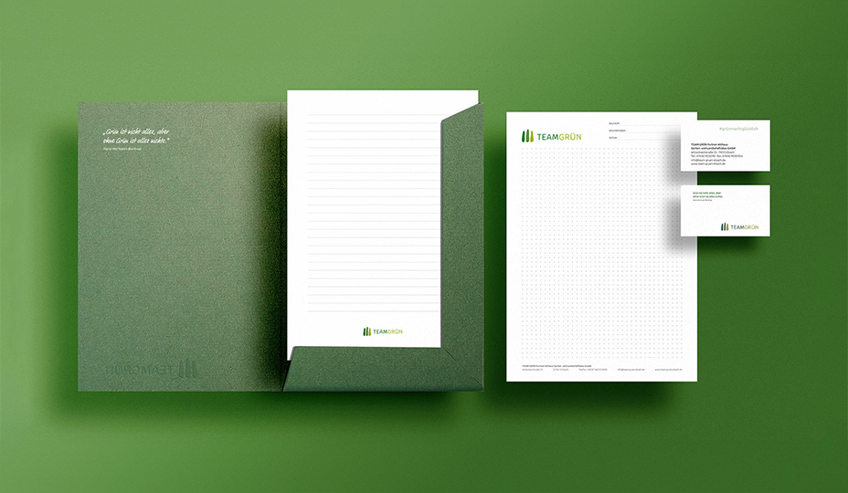 Ansicht einer linierten Papiers in der Präsentationsmappe von Team Grün neben entsprechendem Briefpapier sowie Vorder- und Rückseite