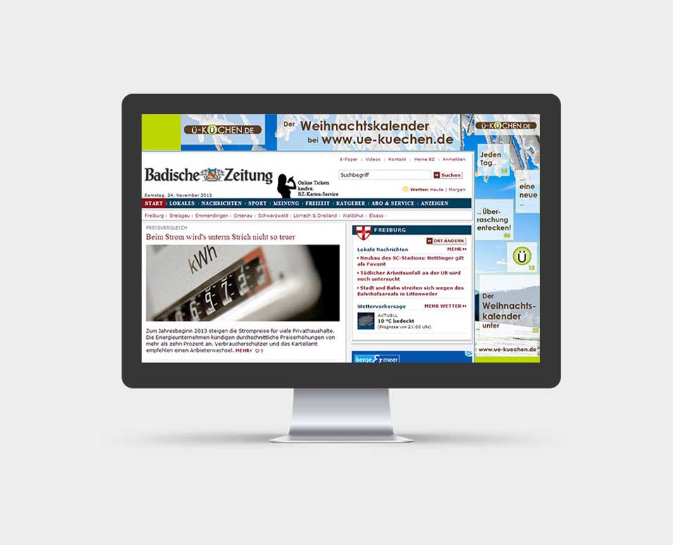 Ansicht der Weihnachtswerbemittel von Ü-Küchen im Web auf einem Monitor vor grauem Hintergrund