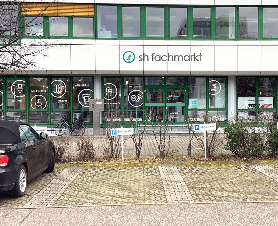 Dartstellung der Fassade mit Fenster-Beklebung des sh fachmarkt und Kundenparkplätzen im Vordergrund