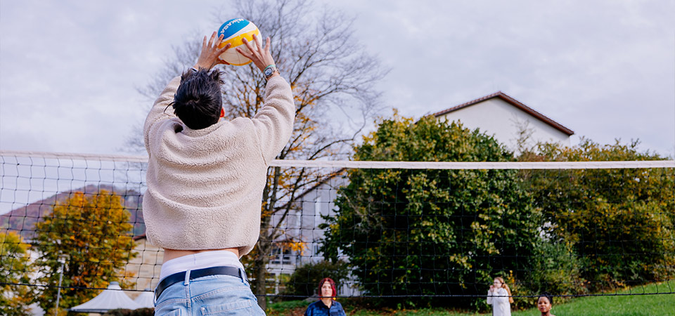 Abbildung eines jugendlichen, der mit seinen Freunden Volleyball im Freien spielt
