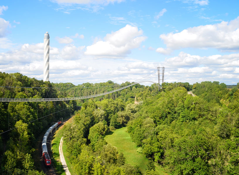 Abbildung eines 3D-Renderings der NECKARLINE über einem Mischwald und einer Bahn.