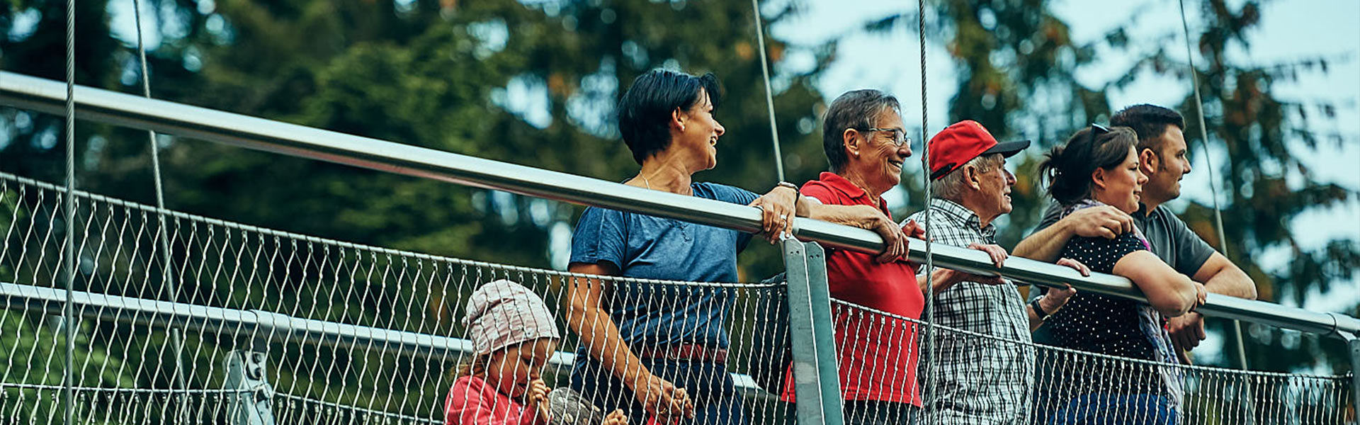Abbildung einer Gruppe Menschen verschiedenen Alters, die die Aussicht auf einer Hängebrücke genießen.